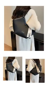 Detail view of black pleated tote bag with golden label and decorative ribbon accessory