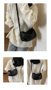 Detail of a black crescent crossbody bag showing its unique fold-over structure and lychee texture