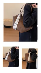 Detail of pleated brown tote bag with decorative white strap and accordion texture