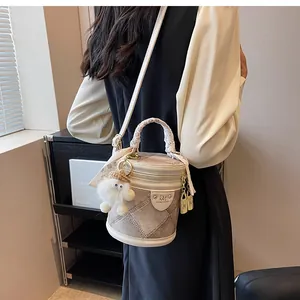 Detail of a chic bucket bag with silk scarf handle, white quilt pattern and plush charm