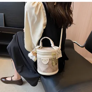Detail of cream bucket bag with silk scarf handle and plush bear charm on a model