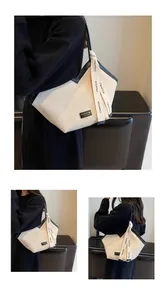 Detail of cream pleated tote bag with black trim and patterned strap on a model
