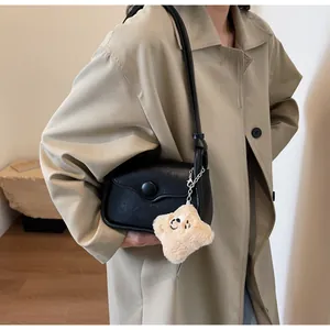 Detailed view of black leather crossbody bag with star pendant and large round buckle