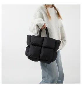 Close-up of black quilted puffer tote bag with glossy finish and soft padding texture