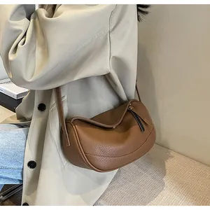 Detail of a brown lychee pattern leather crossbody bag with a gold metal clasp and soft texture