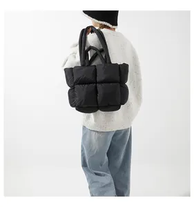 Detail of black quilted down tote bag showing puffy texture and dual handle straps