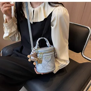 Close-up of light blue denim bucket bag with quilted stitching and silk scarf handle