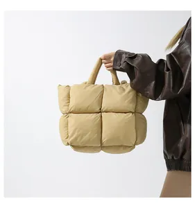 Detail of beige quilted down tote bag with soft padded handle and puffer square texture