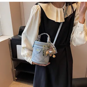 Detail of light blue denim bucket bag with quilted patterns and plaid handle scarf