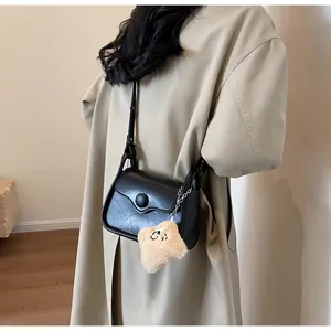 Detail of black crossbody bag with wave design, star charm, and textured faux leather surface