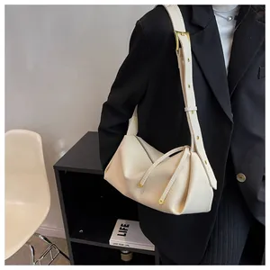 Detail of creamy white pebble grain shoulder bag showing golden metal buckle and zipper