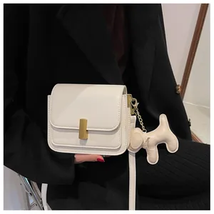Détail du petit sac blanc à boucle dorée et accessoire charmant en forme de chiot