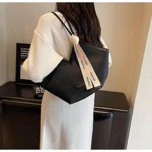 Detailed macro view of black tote bag with pleated texture and decorative silk ribbon