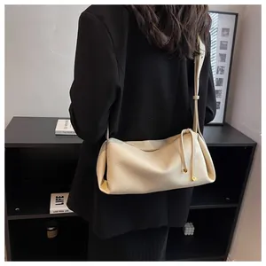 Detail of creamy white pebble leather crossbody bag with drawstring side and metal charm