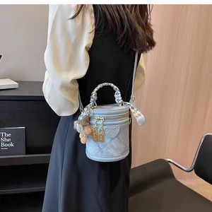 Detail of light blue denim bucket bag with silk scarf handle and plush pendant