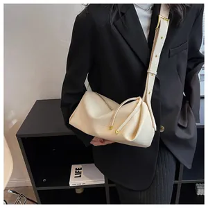 Close-up of ivory pebble leather shoulder bag with gold hardware and folded texture