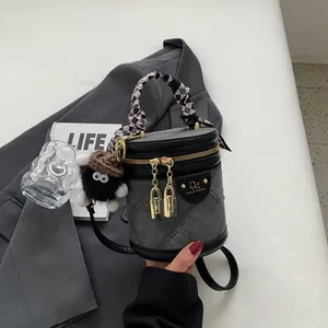 Detail of grey denim bucket bag with checkerboard silk scarf handle and plush pendant
