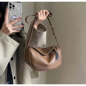 Detailed view of brown lychee texture leather crossbody bag with adjustable strap
