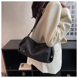 Close-up of black lychee grain leather texture and metallic buckle on crossbody bag