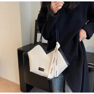 Detail of cream white pleated tote bag featuring black trim and decorative brand ribbon