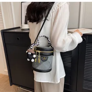 Detail of grey denim bucket bag with checkerboard silk scarf and plush charm accessory