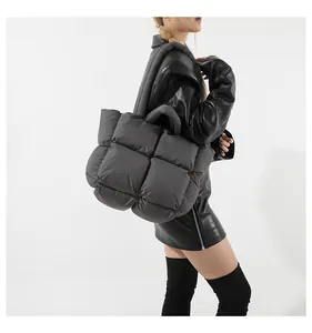 Close-up of dark grey padded puffer tote bag with quilted weave texture on model