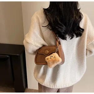 Brown retro flap crossbody bag with decorative round buckle and cute plush charm detail