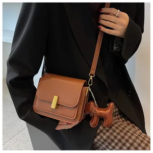 Détail d'un sac bandoulière en cuir marron avec fermoir doré et charmant chiot décoratif