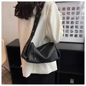 Detail of black pebbled leather crossbody bag with adjustable strap and gold hardware