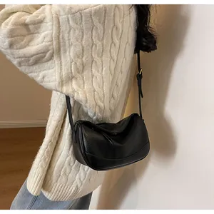 Side view of a black pebbled leather crossbody bag with soft folds on female model