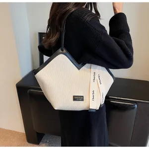 Detail of the pleated cream tote bag with contrast black trim and branded ribbon strap