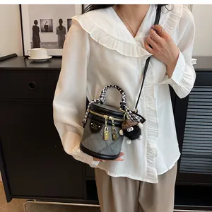 Detailed view of grey fabric bucket bag with silk scarf handle and plush pendant