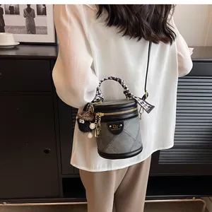 Detail of bucket bag featuring checkered scarf handle and plush monster charm