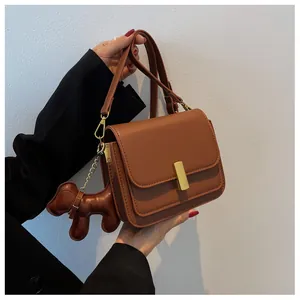 Détail du sac à bandoulière marron chaud avec fermoir doré et breloque chien