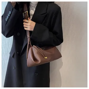 Detail of dark brown lychee leather texture and golden metal buckle on the crossbody bag