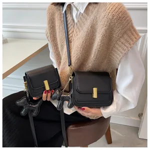 Détails du sac bandoulière noir avec fermoir doré et pendentif en forme de petit chien