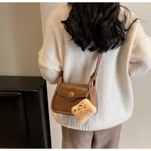 Brown vintage crossbody bag featuring a plush star charm on a female model back view