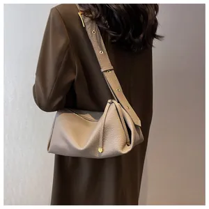 Detail of grey lychee leather shoulder bag with gold metal eyelets on wide strap