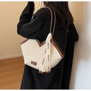 Detail of cream pleated tote bag with brown leather trim shown on a model