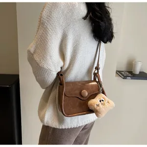 Detail of a brown leather crossbody bag with star charm against a fashion book background