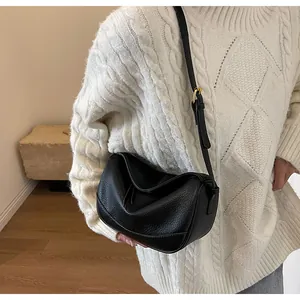 Detail view of black lychee-textured leather crossbody bag on model shoulder