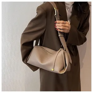 Detail of taupe litchi grain leather texture and gold hardware on minimalist bag