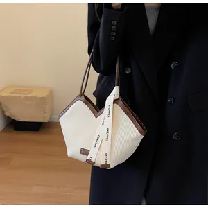 Close-up of the pleated fabric texture and brown leather trim on the V-shaped tote bag