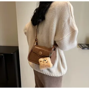 Detail of dark brown retro crossbody bag with cute plush toast pendant on a knit sweater