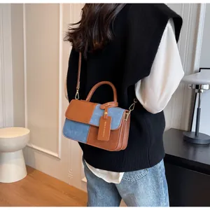 Detalle del bolso vintage color-block en denim azul y cuero marrón con herrajes de oro