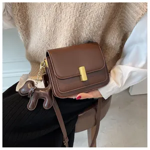 Détail du sac bandoulière marron avec boucle dorée et charmant pendentif en cuir en forme de chien