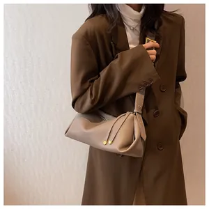 Detail of khaki pebbled leather shoulder bag featuring unique pleated design and gold metal accents