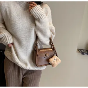 Detail of dark brown retro crossbody bag with matte finish and star plush charm