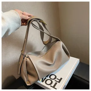 Detailed close-up of taupe pebbled leather texture on a stylish pillow bag with gold hardware