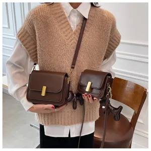 Détail de sacs bandoulière marron en simili cuir avec boucles dorées et breloque